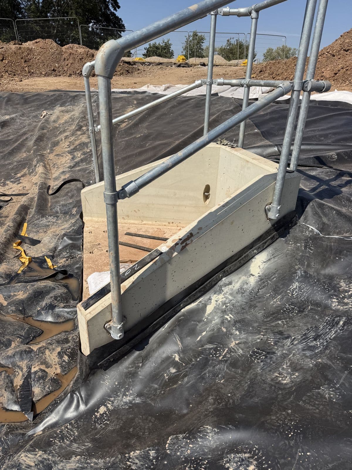 HDPE liner sealed around a concrete headwall at the HS2 pond