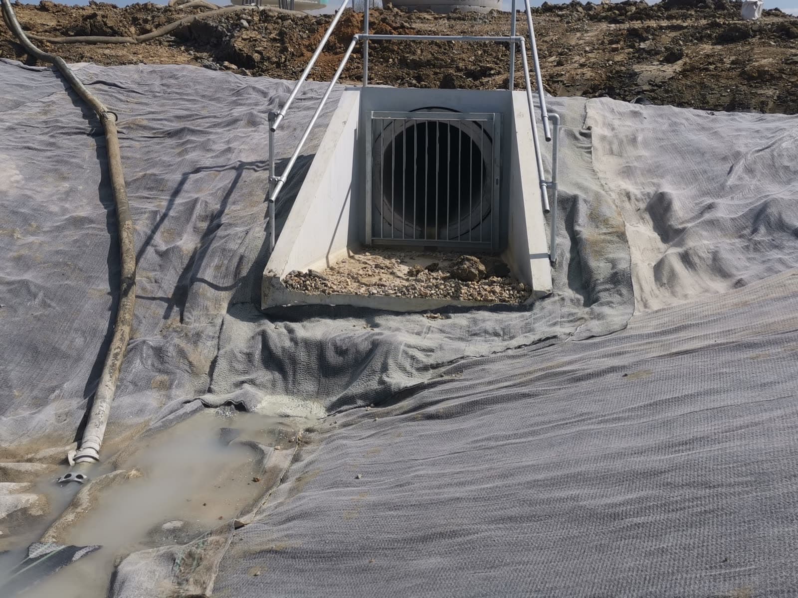 Close-up of needle-punched geosynthetic clay liner dressed around a concrete outfall headwall