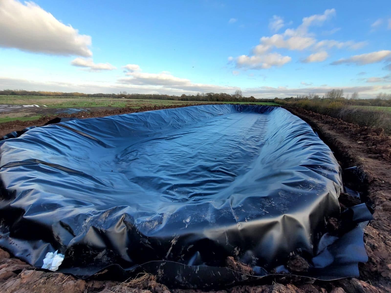 A pond basin fully lined with geomembrane dressed up the banks